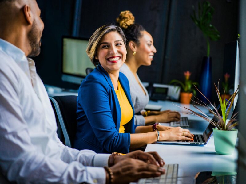 Three cheerful employees working at laptops.
