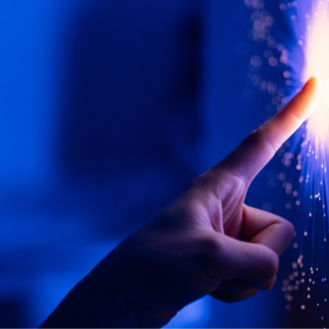 Finger touching a screen and creating a sparkling effect against a blue background