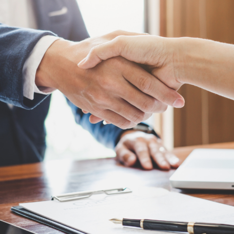 Executives make a deal with a handshake over a desk