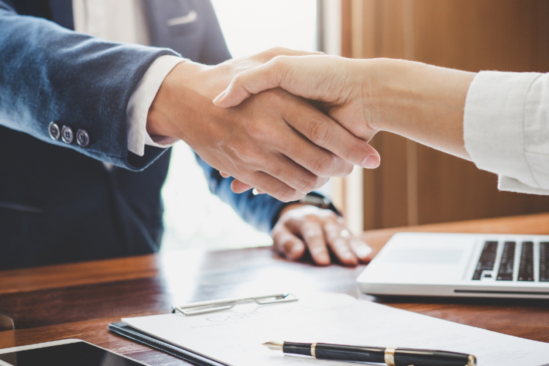 Executives make a deal with a handshake over a desk