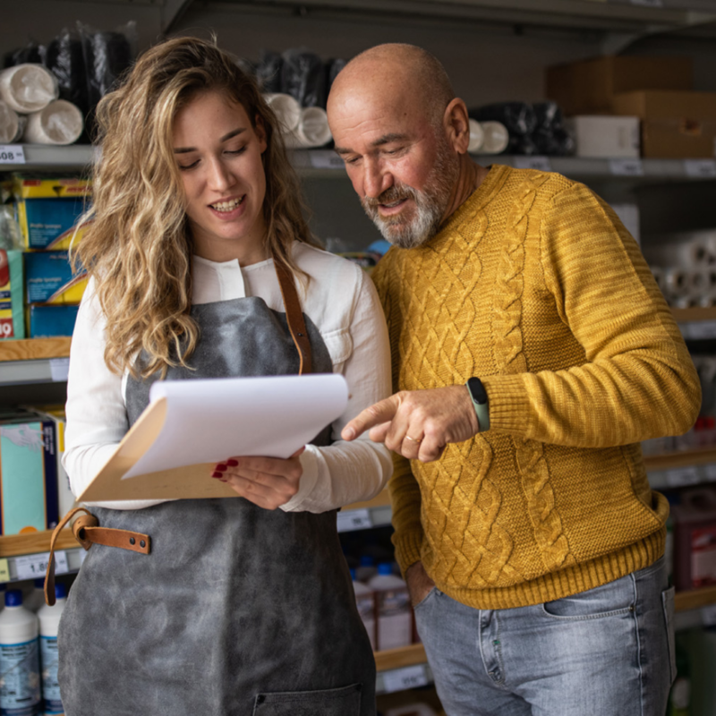 Workers review documents while standing in front of items on a store shelf