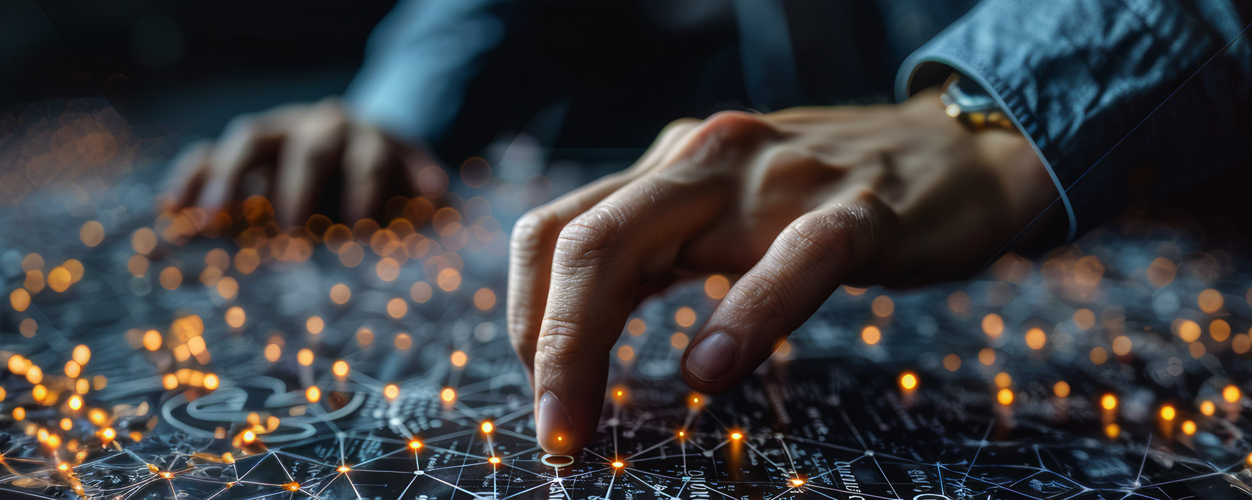 two hands hover over a table, which is covered in interconnected circuits. Some of the circuits are lit up orange.