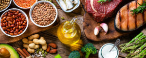 a collection of food on a table with meat, bean, oil, and vegetables. 