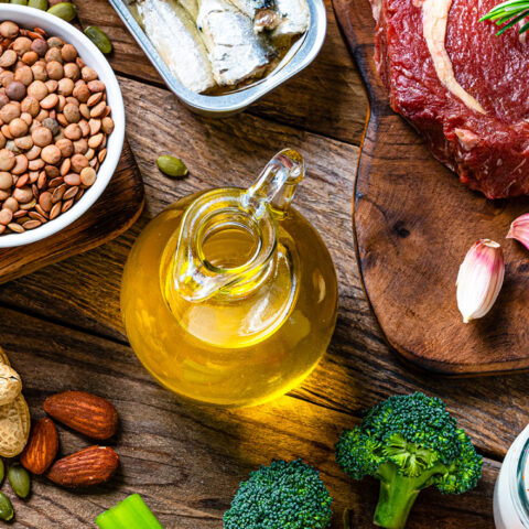 a collection of food on a table with meat, bean, oil, and vegetables.